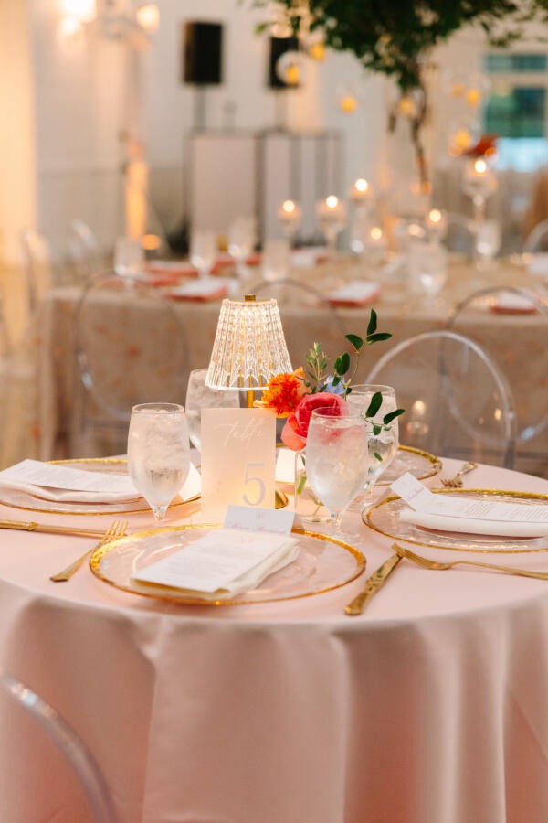 Elegant wedding decor Houston setup with luxury linens, gold chargers, and floral centerpiece by EB Inc Events.
