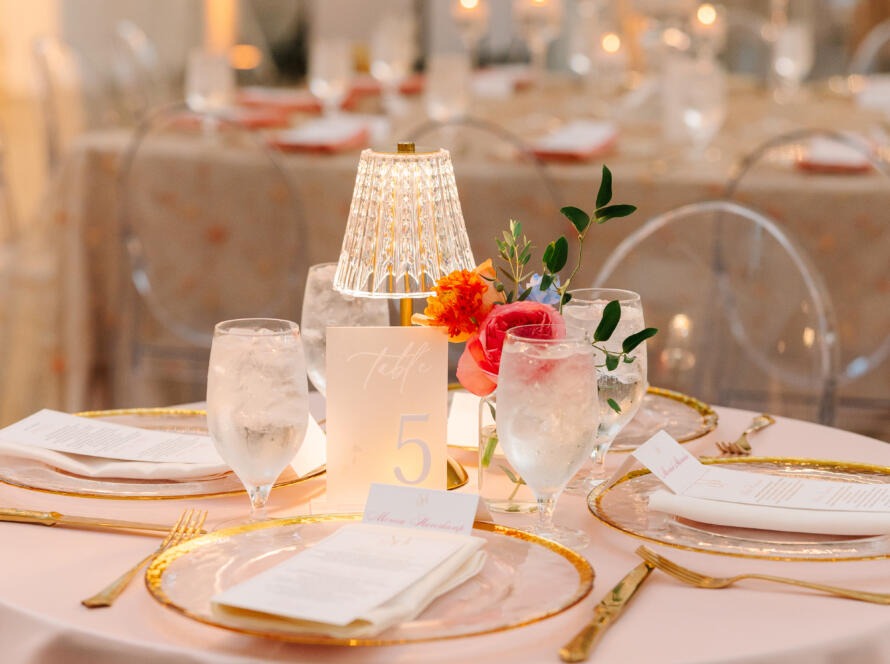 Elegant wedding decor Houston setup with luxury linens, gold chargers, and floral centerpiece by EB Inc Events.