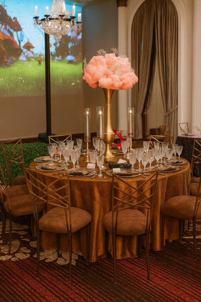 Luxury event rentals Houston table setup with gold centerpiece, crystal glassware, and elegant bronze seating