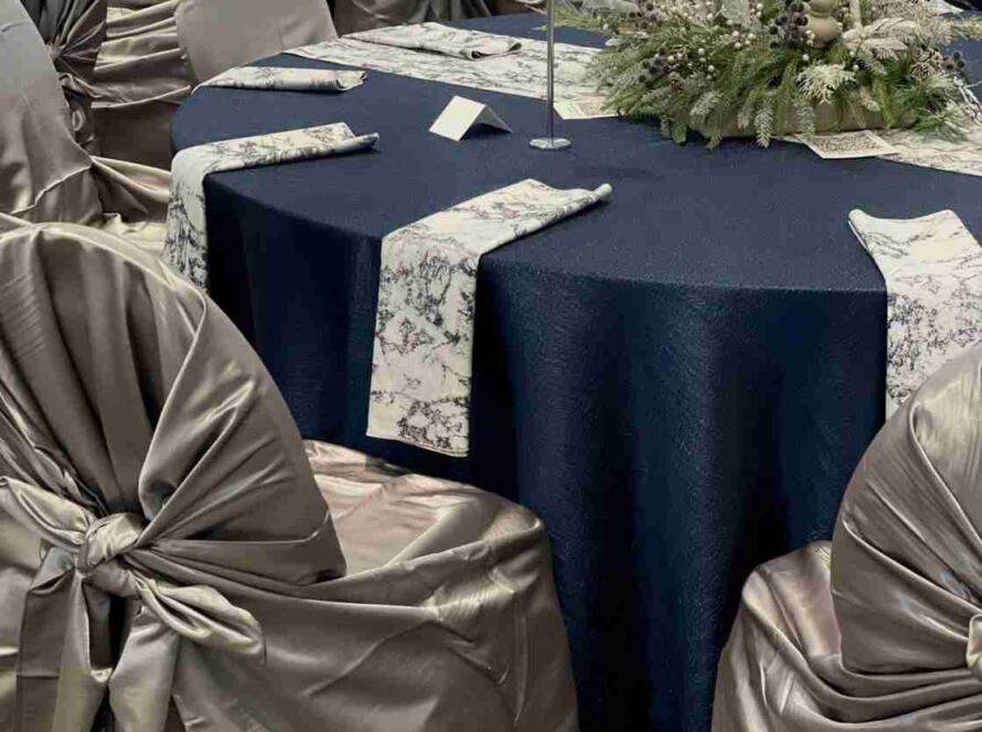 Chair cover rentals Houston reception with champagne self-tie covers and navy tablecloths