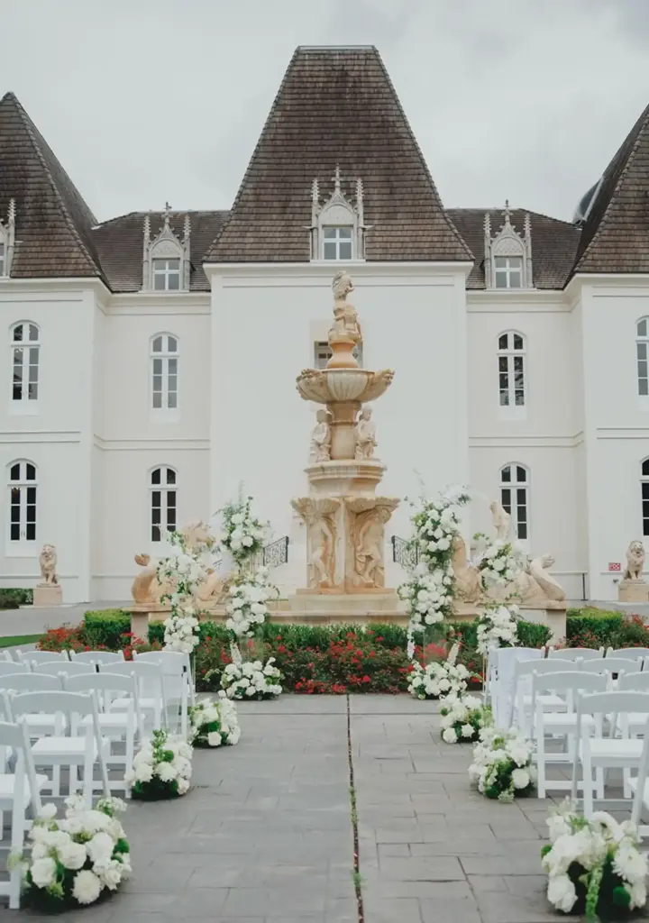 Outdoor wedding ceremony with white chairs and white floral aisle arrangements at a Houston-area venue
